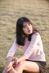 Portrait of young woman sitting on field