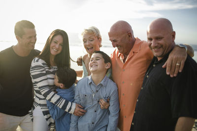 Happy family standing at beach against sky