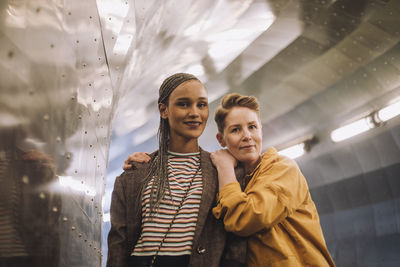Portrait of smiling lesbian couple standing in illuminated tunnel