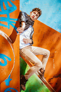 Full length portrait of young man against graffiti wall