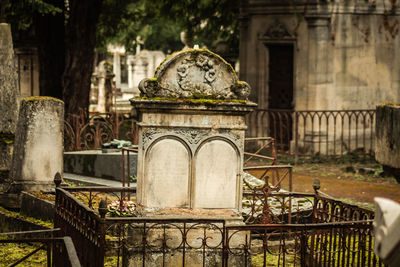 View of cross in cemetery against old building