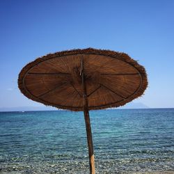 Parasol at beach against clear blue sky