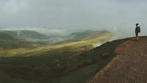 Rear view of man looking at mountains against sky