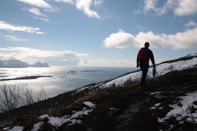 Rear view of man walking in sea against sky