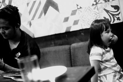 Tilt shot of girl sitting on sofa while looking away with mouth open at restaurant