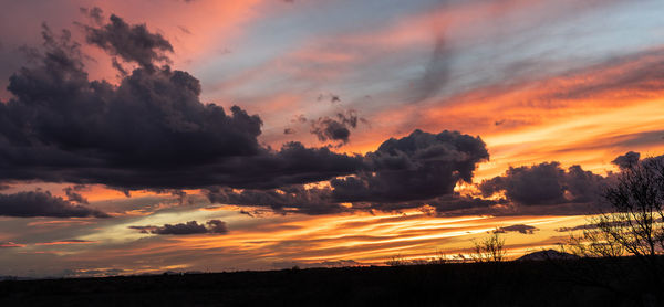 Scenic view of dramatic sky over silhouette landscape during sunset