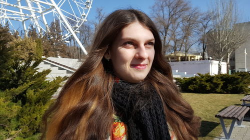 Smiling woman with long brown hair looking away on sunny day