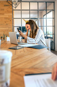 Woman using mobile phone while sitting on table