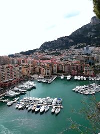 Boats moored in harbor against buildings in city