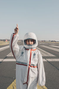 Astronaut girl pointing to the sky looking at the camera, girl power and feminism concept