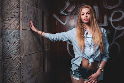 Portrait of woman standing by wall