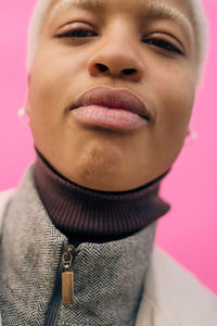 Close-up portrait of contemplating young female standing against pink background