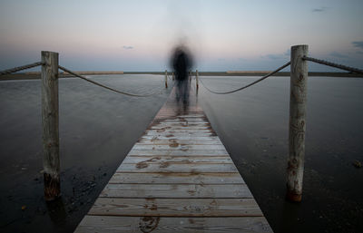 Pier on footbridge against sky during foggy weather