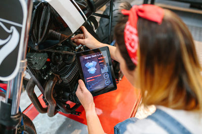 Mechanic woman using engine diagnosis app to review motorcycle