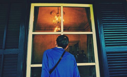 Rear view of man looking through window