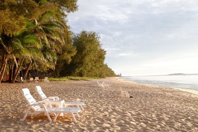 Chairs on beach against sky