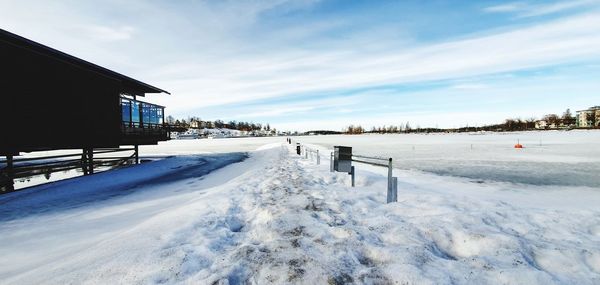Snow covered land by buildings against sky