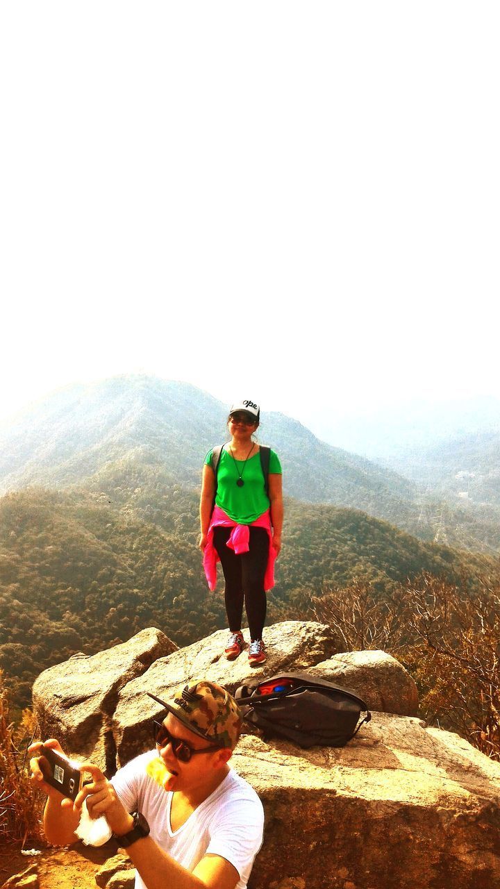 FULL LENGTH OF YOUNG WOMAN STANDING ON MOUNTAIN ROAD