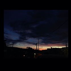 Silhouette of power lines against cloudy sky