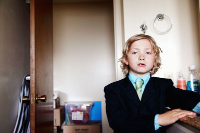 Close-up portrait of boy wearing suit standing by door at home