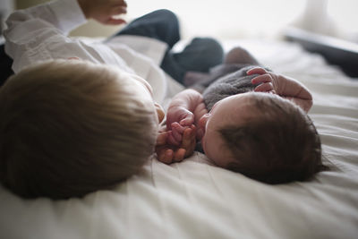 Boy lying by newborn brother on bed at home