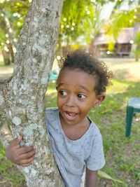 Portrait of cute baby boy against tree trunk