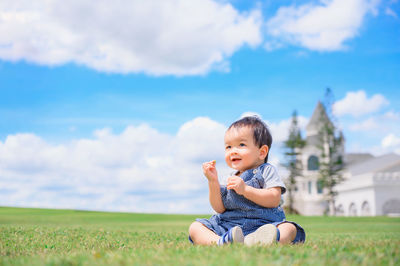 Cute baby girl on field against sky