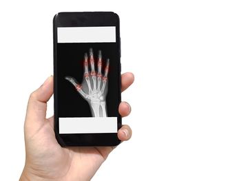 Close-up of hand holding smart phone over white background