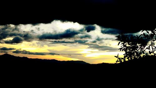 Silhouette landscape against dramatic sky during sunset
