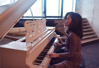 Side view of young woman playing piano