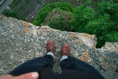 Low section of man standing on retaining wall against trees