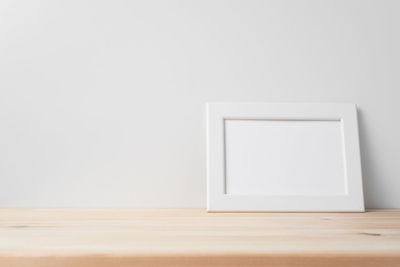 Close-up of empty wooden table against wall at home