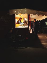 Man standing at cafe in city at night