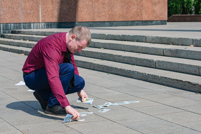 Businessman dropped a lot of money on the ground and picks it up