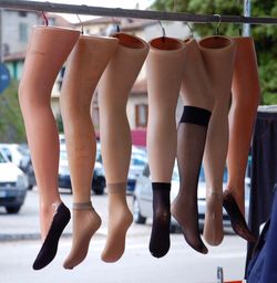 Low section of artificial legs with socks and stockings hanging on rod