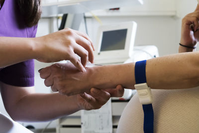 Cropped hands of nurse putting iv needle into patient hand at hospital