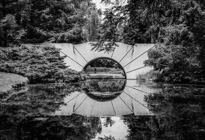 Digital composite image of arch bridge over lake in forest