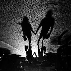 Low section of silhouette people against bare tree