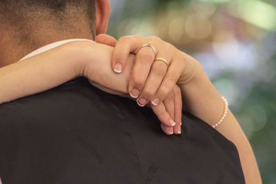 Cropped hands of woman around man neck