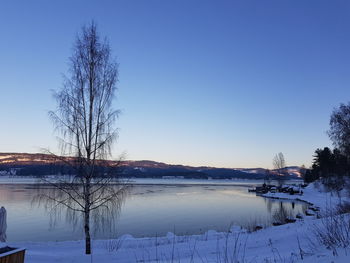 Scenic view of frozen lake against clear blue sky