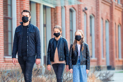 Father and daughters wearing masks while walking outdoors