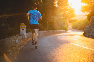 Rear view of man skateboarding on road