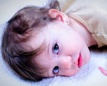 Portrait of cute baby girl lying on bed