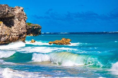 Scenic view of rocks in sea against blue sky