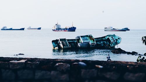 Fishing boats on sea against clear sky