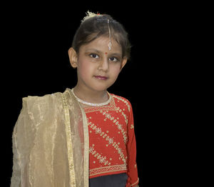 Portrait of cute girl wearing traditional clothing against black background