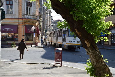 Rear view full length of man walking by cable car on street in city