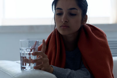 Portrait of beautiful young woman drinking glass on table