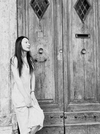 Young woman standing against door