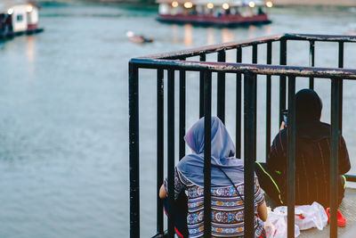 Rear view of men on railing by river